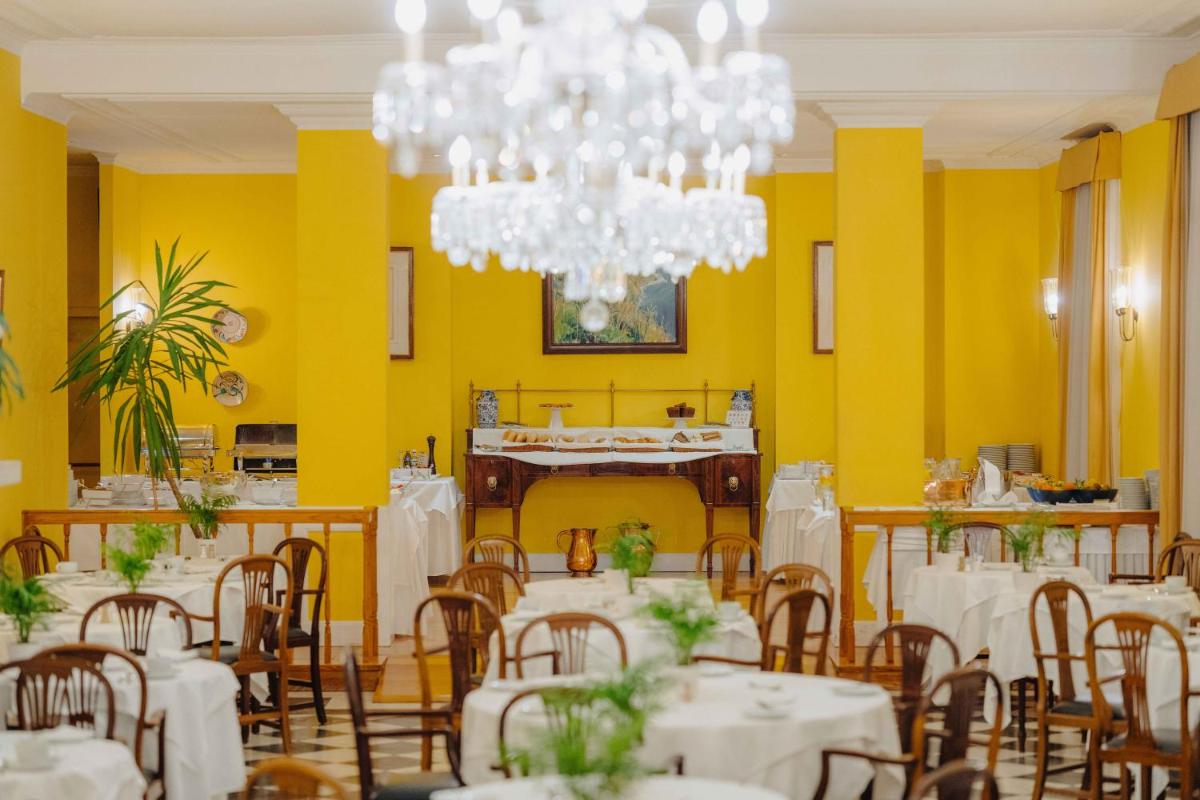 uma sala de jantar com mesas e cadeiras e um lustre em Quinta da Bela Vista no Funchal