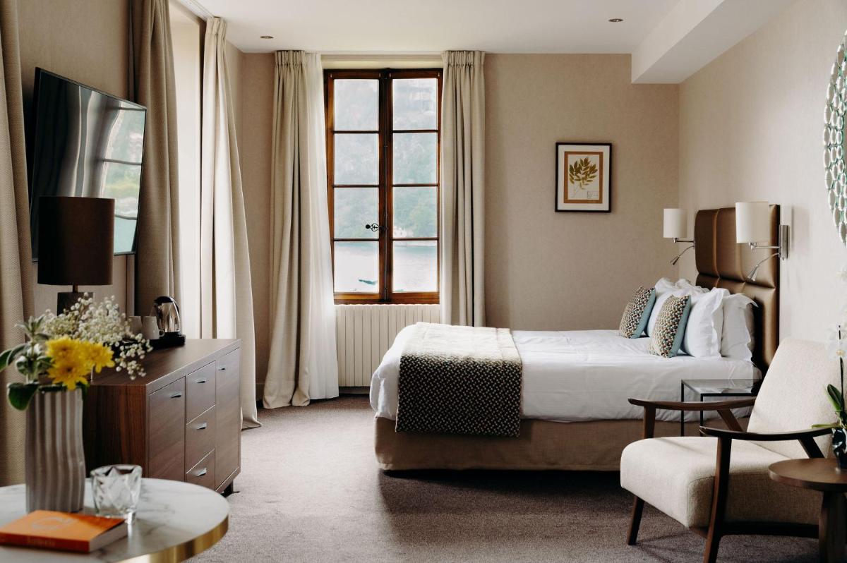 une chambre d'hôtel avec un lit et une chaise dans l'établissement Hotel Le Cottage Bise, à Talloires