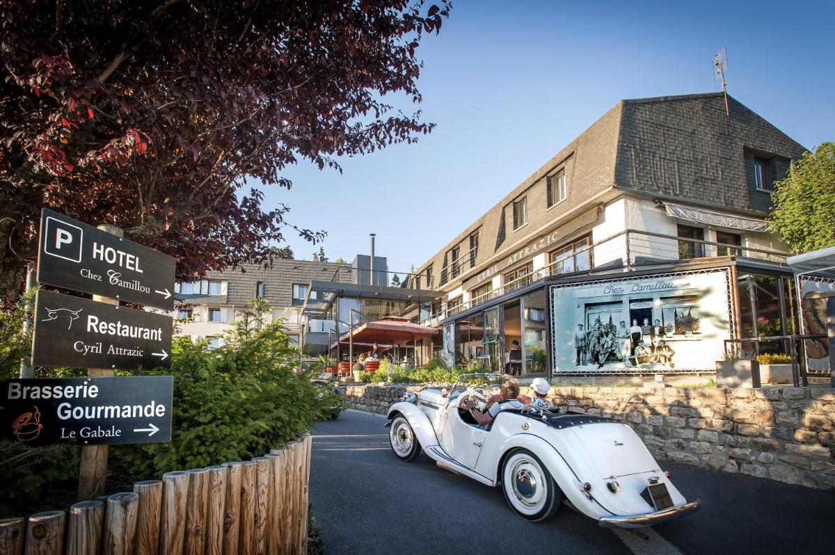 Une vieille voiture blanche qui descend dans une rue dans l'établissement Logis Hôtel et Spa Chez Camillou, à Aumont-Aubrac