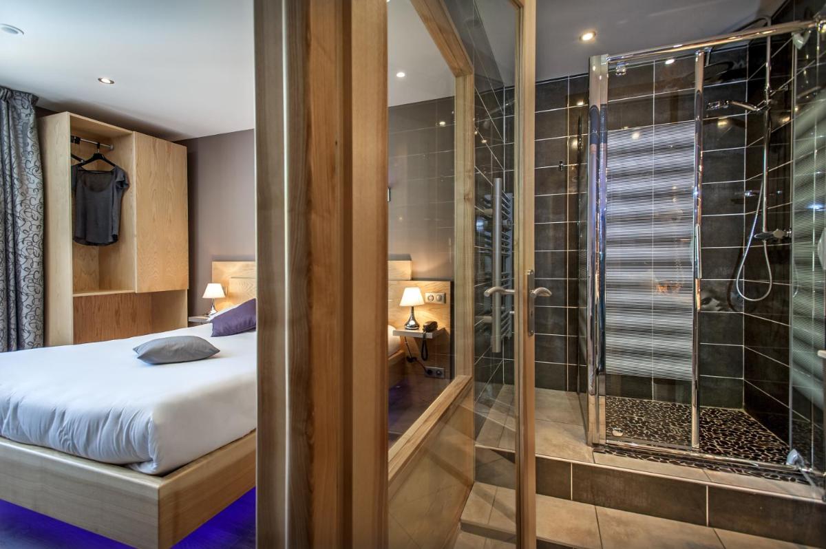 une chambre avec un lit et une douche en verre dans l'établissement Logis Hôtel et Spa Chez Camillou, à Aumont-Aubrac