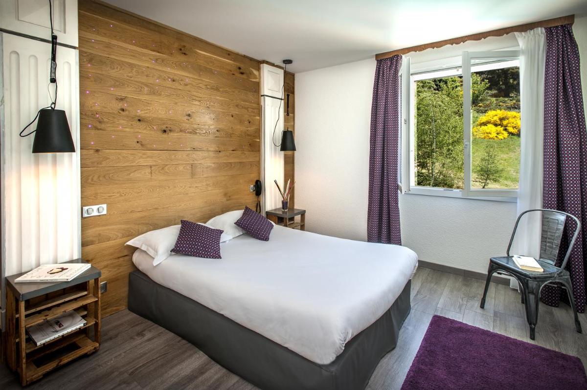 une chambre d'hôtel avec un lit et une fenêtre dans l'établissement Logis Hôtel et Spa Chez Camillou, à Aumont-Aubrac