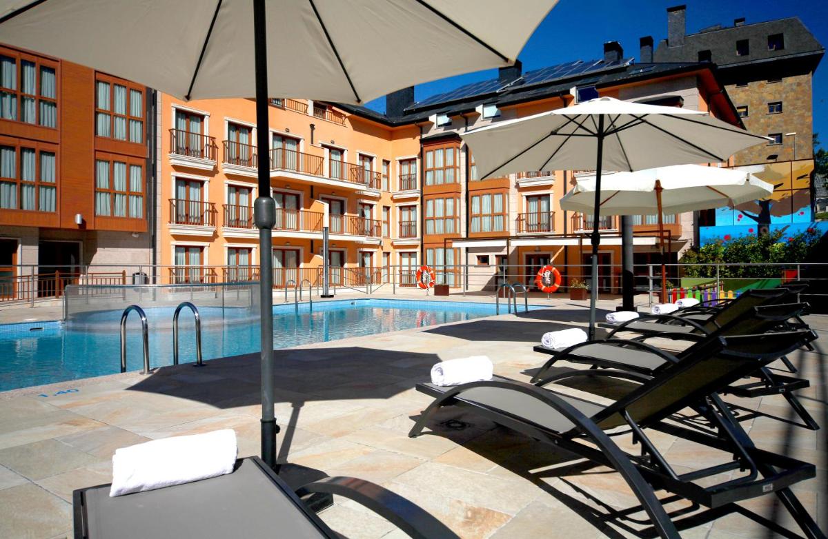 Un grupo de sillas y sombrillas junto a una piscina. en Apartahotel & Spa Jacetania, en Jaca