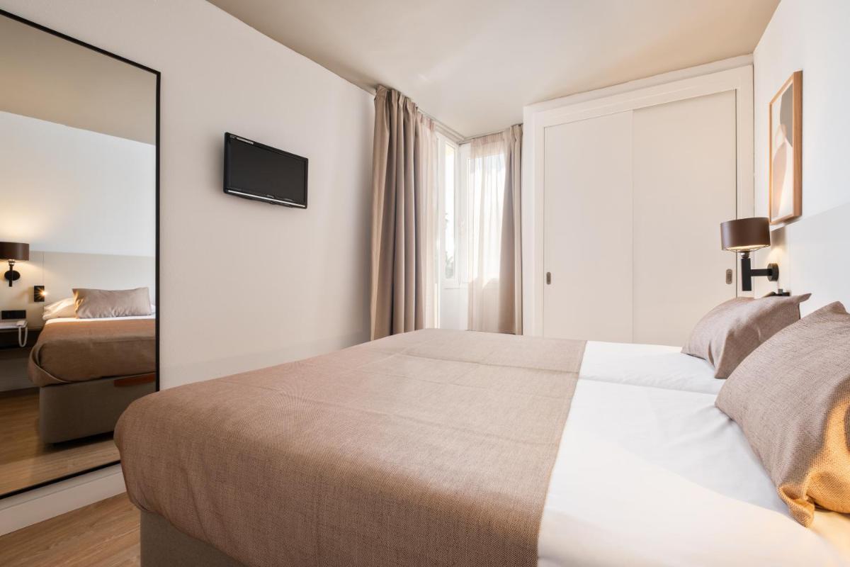 Un dormitorio con una cama grande y un espejo. en Aparthotel Duva & Spa, en Puerto Pollensa