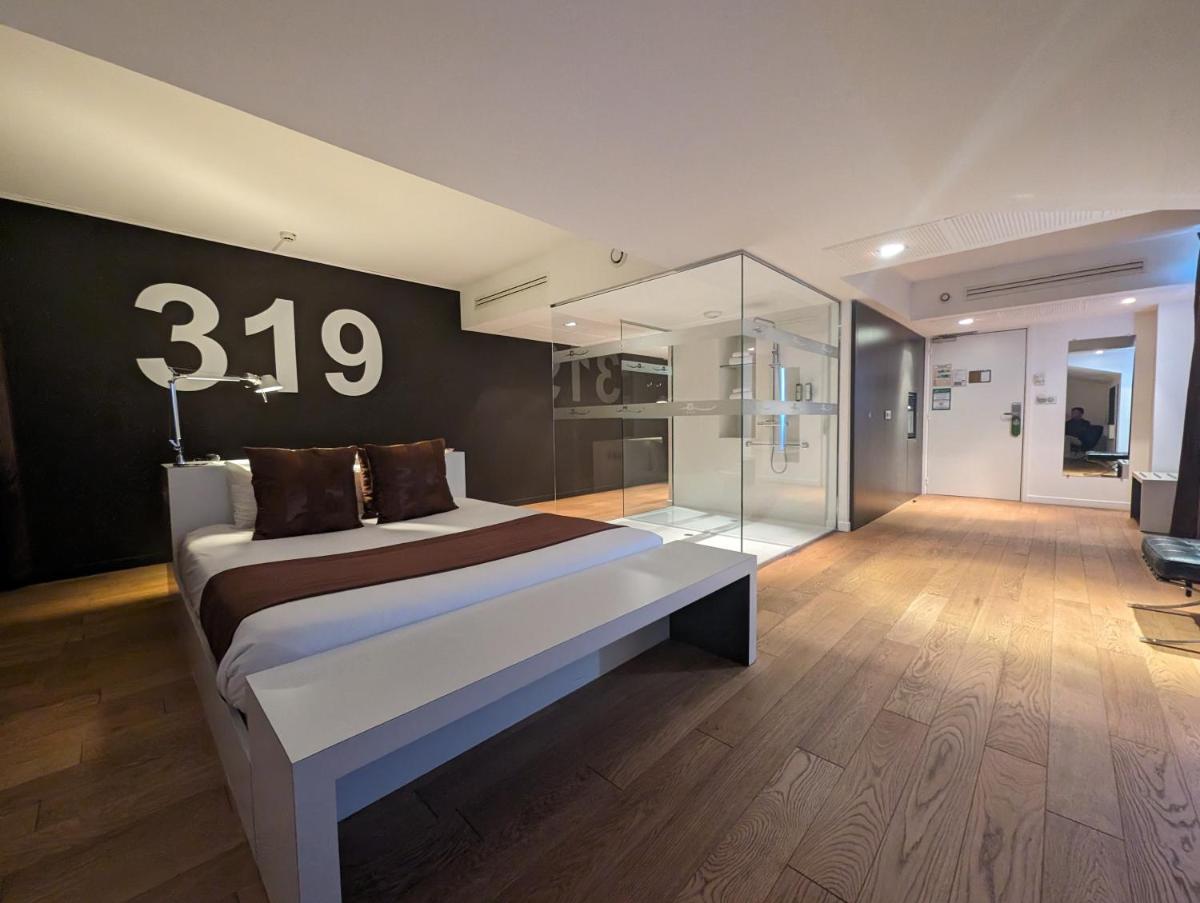 - une chambre dotée d'un grand lit avec un numéro sur le mur dans l'établissement Hotel L'Hotan, à Portet-sur-Garonne