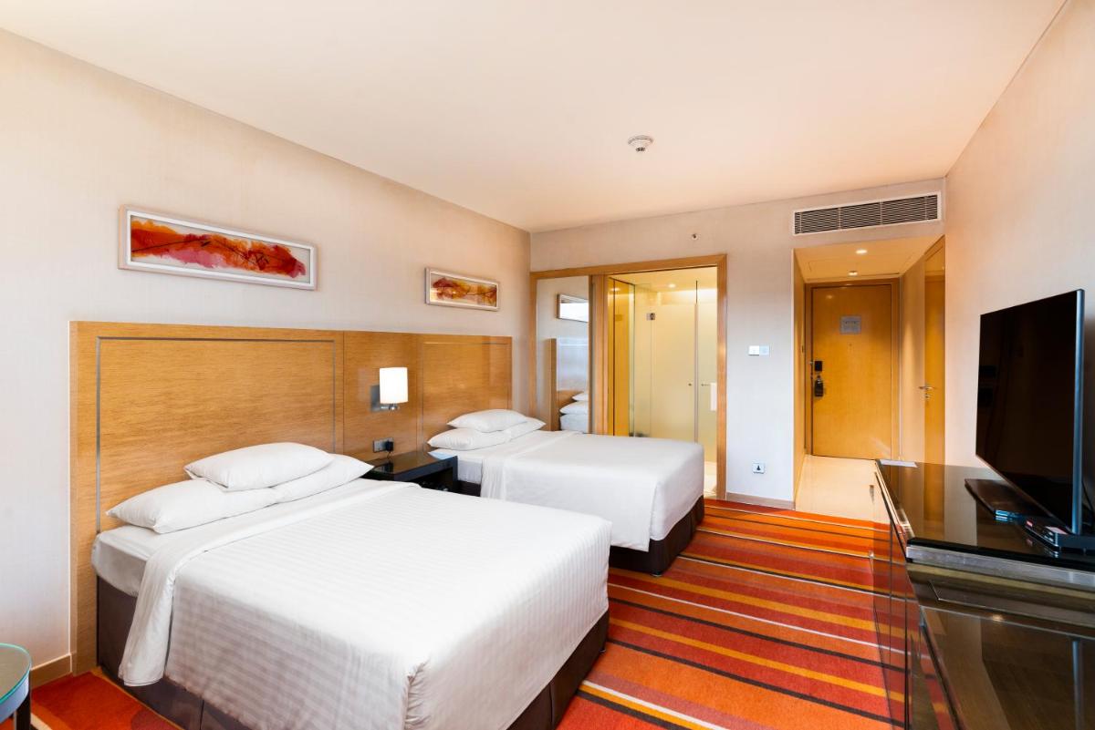 a hotel room with two beds and a flat screen tv at Courtyard by Marriott Pune Hinjewadi in Pune