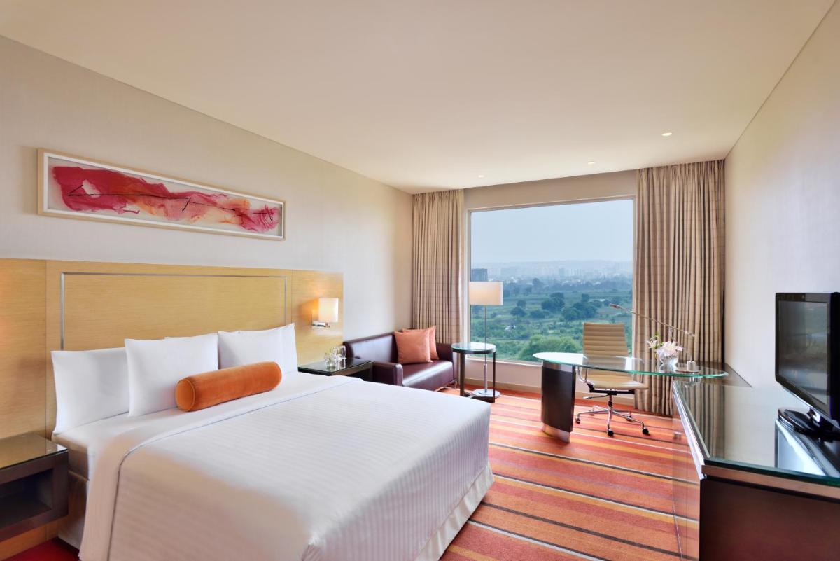 a hotel room with a bed and a large window at Courtyard by Marriott Pune Hinjewadi in Pune