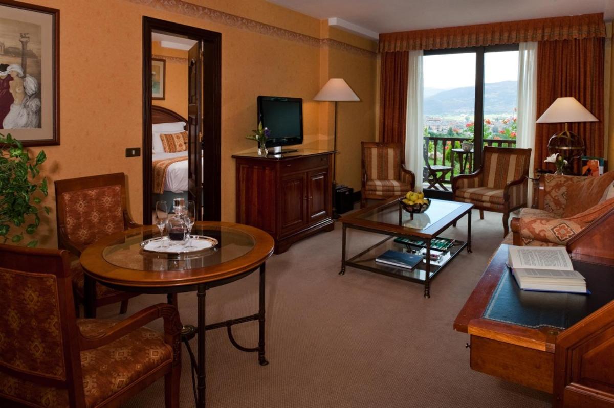 una sala de estar con sofá y una habitación con TV en HOTEL & SPA El Castell de Ciutat, en La Seu d'Urgell