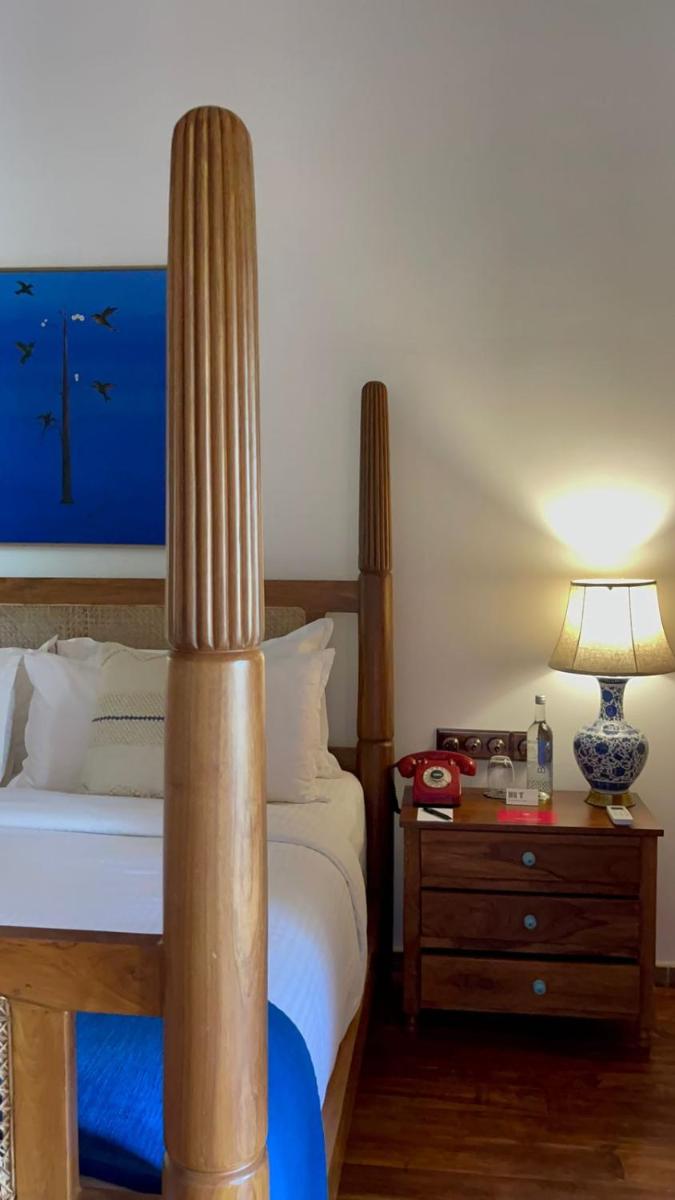 a bedroom with a bed and a table with a lamp at The Postcard Saligao in Calangute