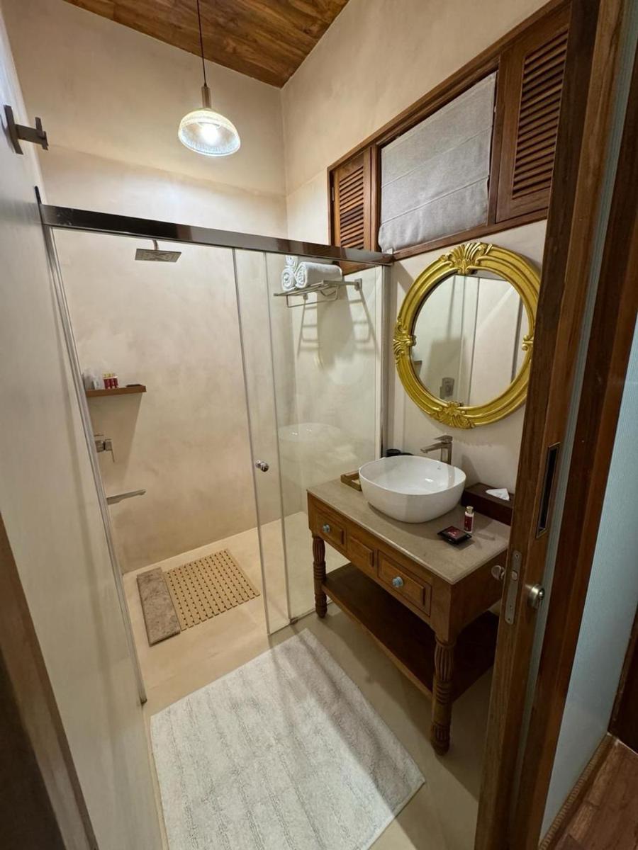 a bathroom with a sink and a shower with a mirror at The Postcard Saligao in Calangute