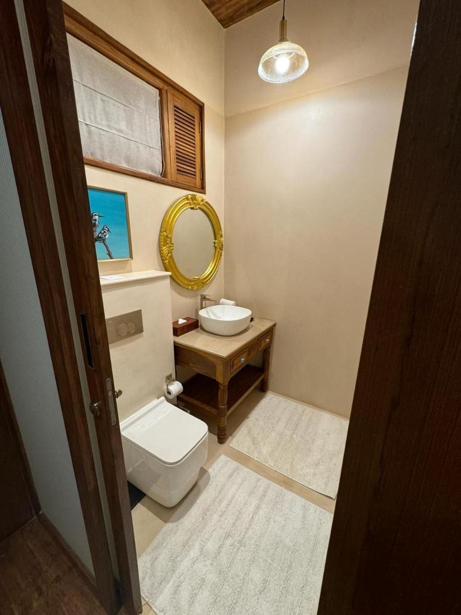a bathroom with a toilet and a sink and a mirror at The Postcard Saligao in Calangute