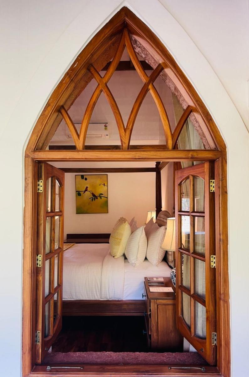 a bedroom with a large arched window with a bed at The Postcard Saligao in Calangute