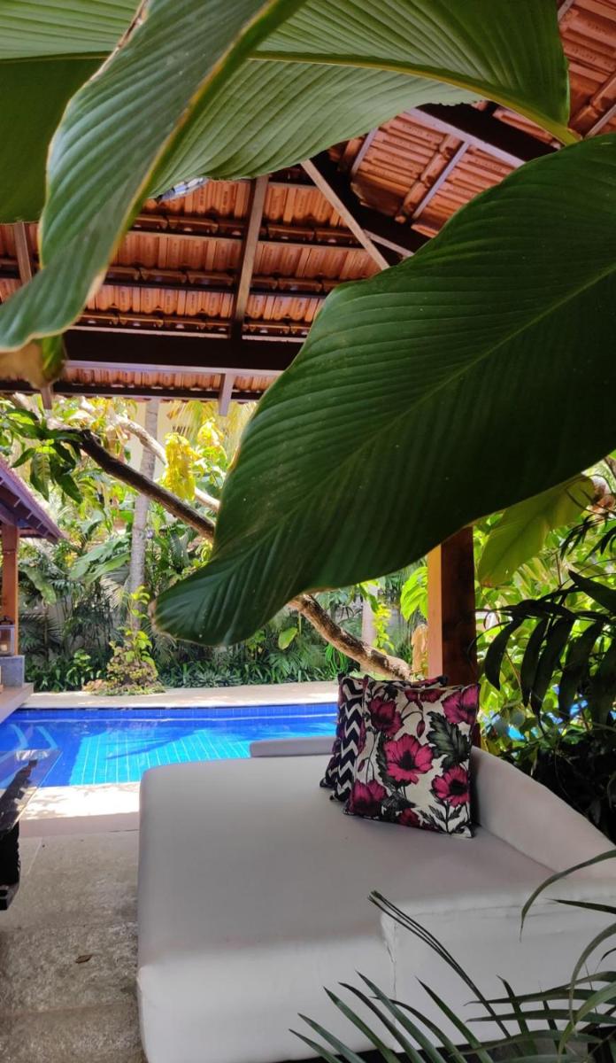 a white couch with a pillow sitting next to a pool at The Postcard Saligao in Calangute