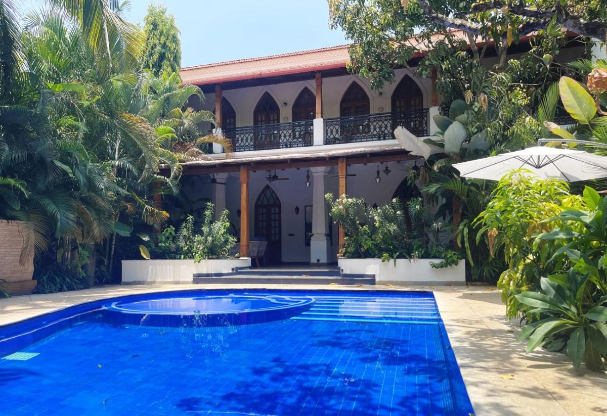 a swimming pool in front of a house at The Postcard Saligao in Calangute