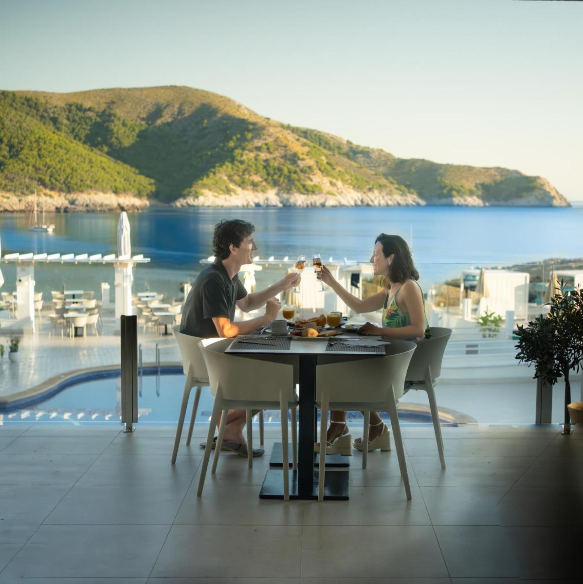 Un hombre y una mujer sentados en una mesa con vasos. en Parque Nereida Suites Hotel, en Cala Ratjada