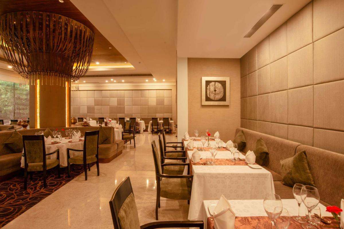 a dining room with tables and chairs in a restaurant at Radisson Blu Bengaluru Outer Ring Road in Bengaluru