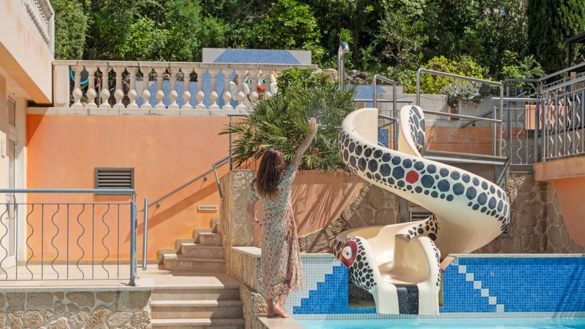 une femme debout sur un toboggan en forme de dauphin dans une piscine dans l'établissement Résidence les Tourelles, à Sainte-Maxime