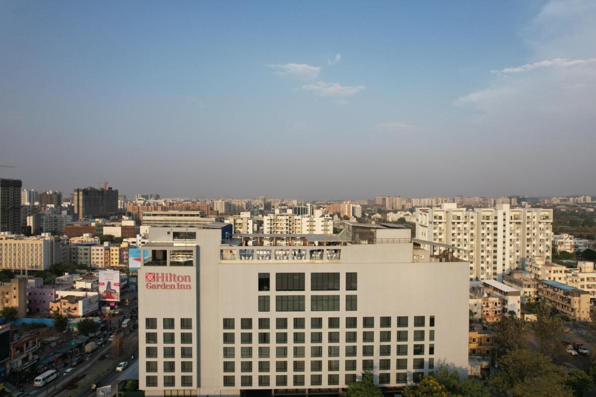 a tall white building in a city with buildings at Hilton Garden Inn Pune Hinjawadi in Pune