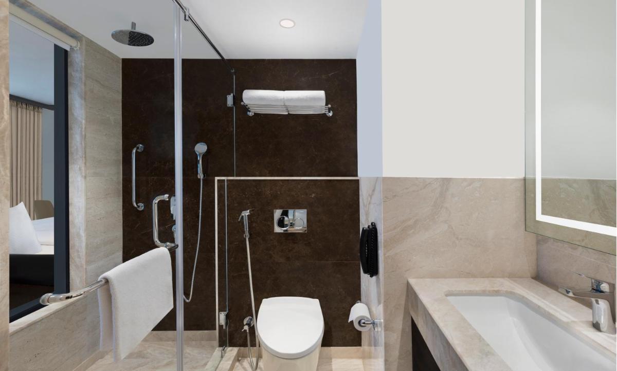 a bathroom with a tub and a toilet and a sink at Hilton Garden Inn Pune Hinjawadi in Pune