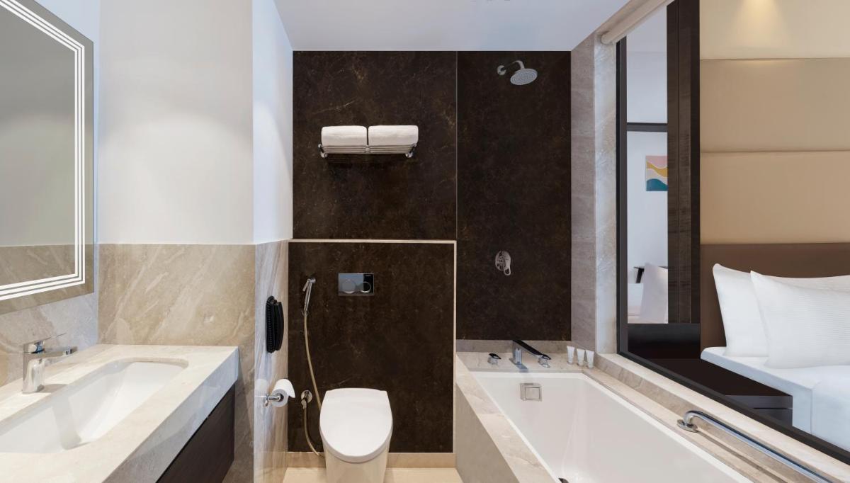 a bathroom with a toilet and a sink and a tub at Hilton Garden Inn Pune Hinjawadi in Pune