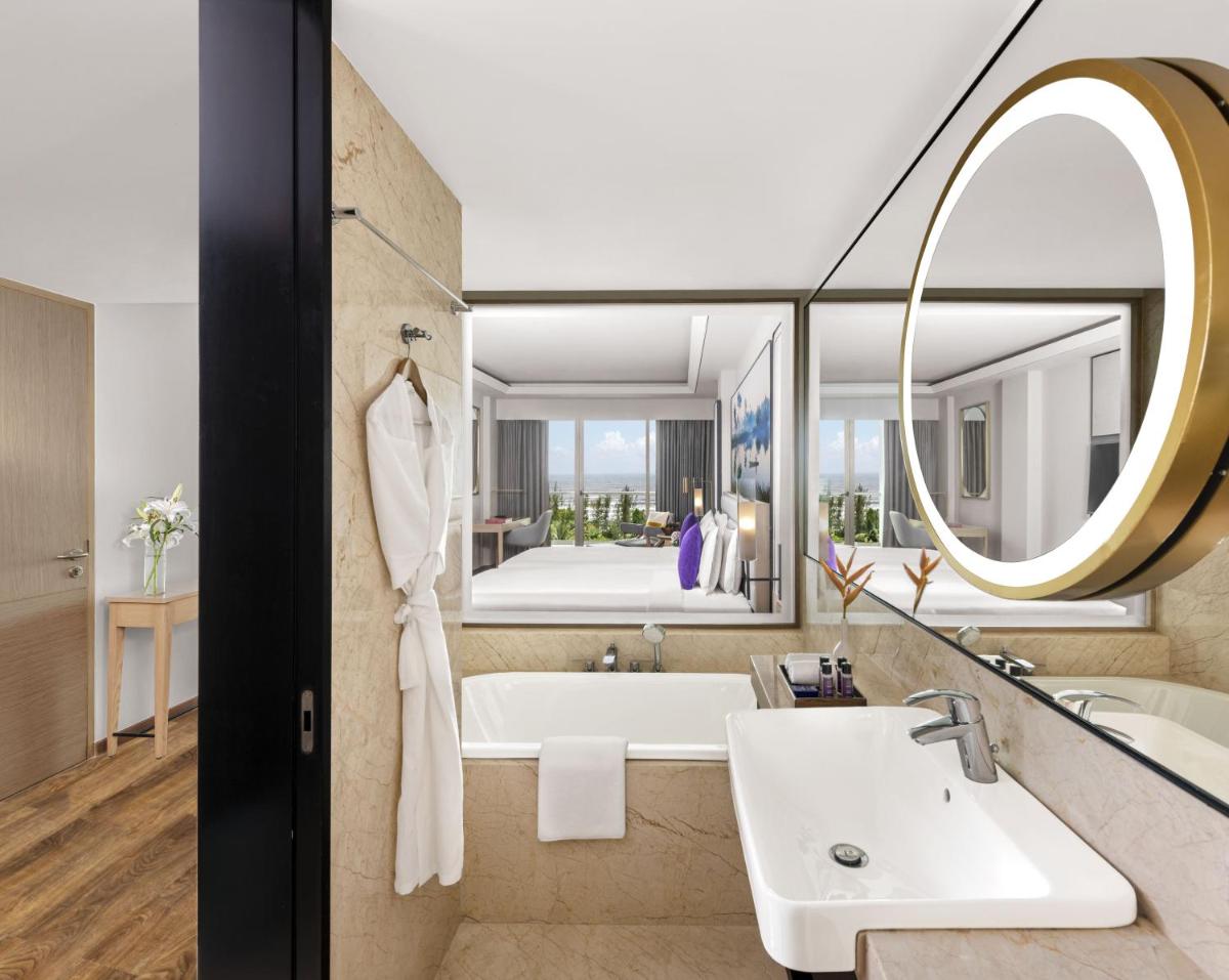 a bathroom with a tub and a sink and a mirror at Vivanta Goa, Miramar in Panaji a bathroom with a tub and a sink and a mirror at Vivanta Goa, Miramar in Panaji