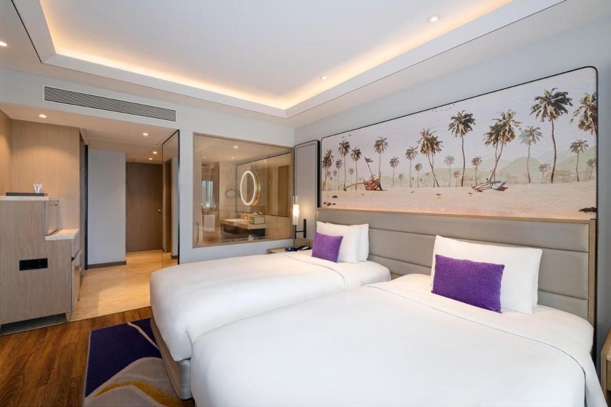 two beds in a hotel room with purple pillows at Vivanta Goa, Miramar in Panaji two beds in a hotel room with purple pillows at Vivanta Goa, Miramar in Panaji