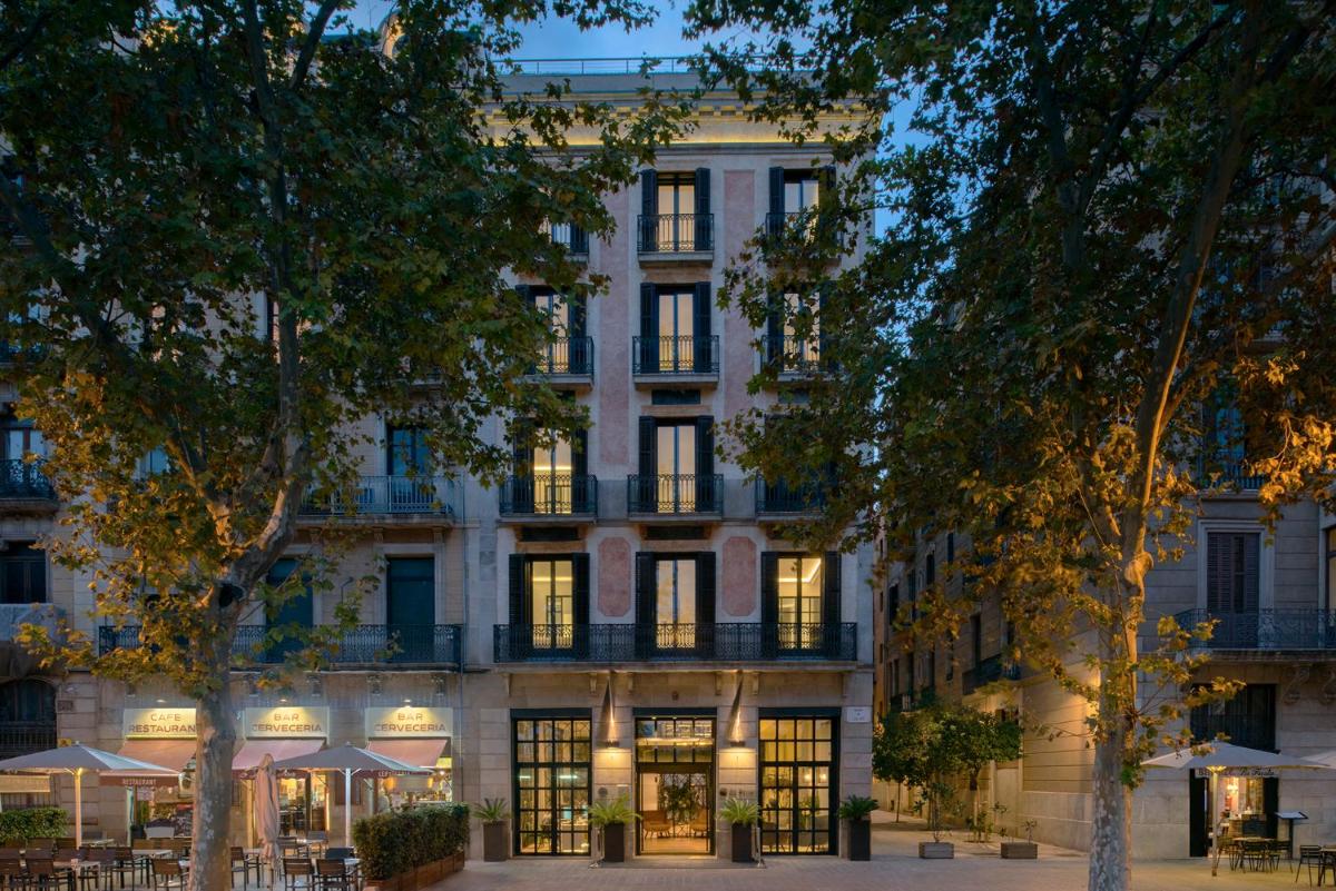 Una vista exterior de un edificio con mesas y sombrillas. en Serras Barcelona, en Barcelona