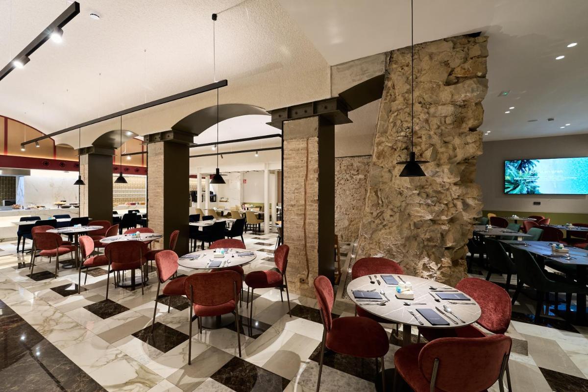 Un restaurante con mesas y sillas y una pared de piedra. en Catalonia Plaza Catalunya, en Barcelona