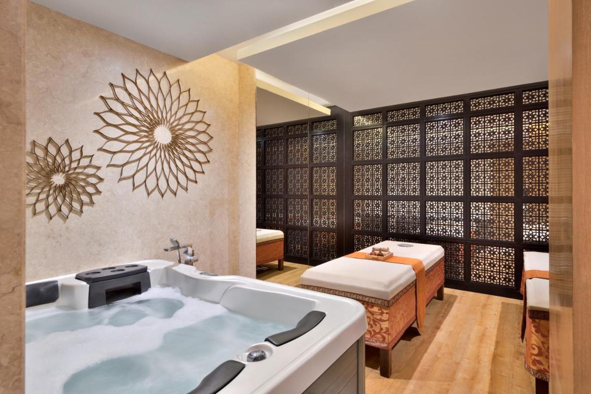 a bathroom with a tub and a bed in a room at Marriott Executive Apartment - Lakeside Chalet, Mumbai in Mumbai