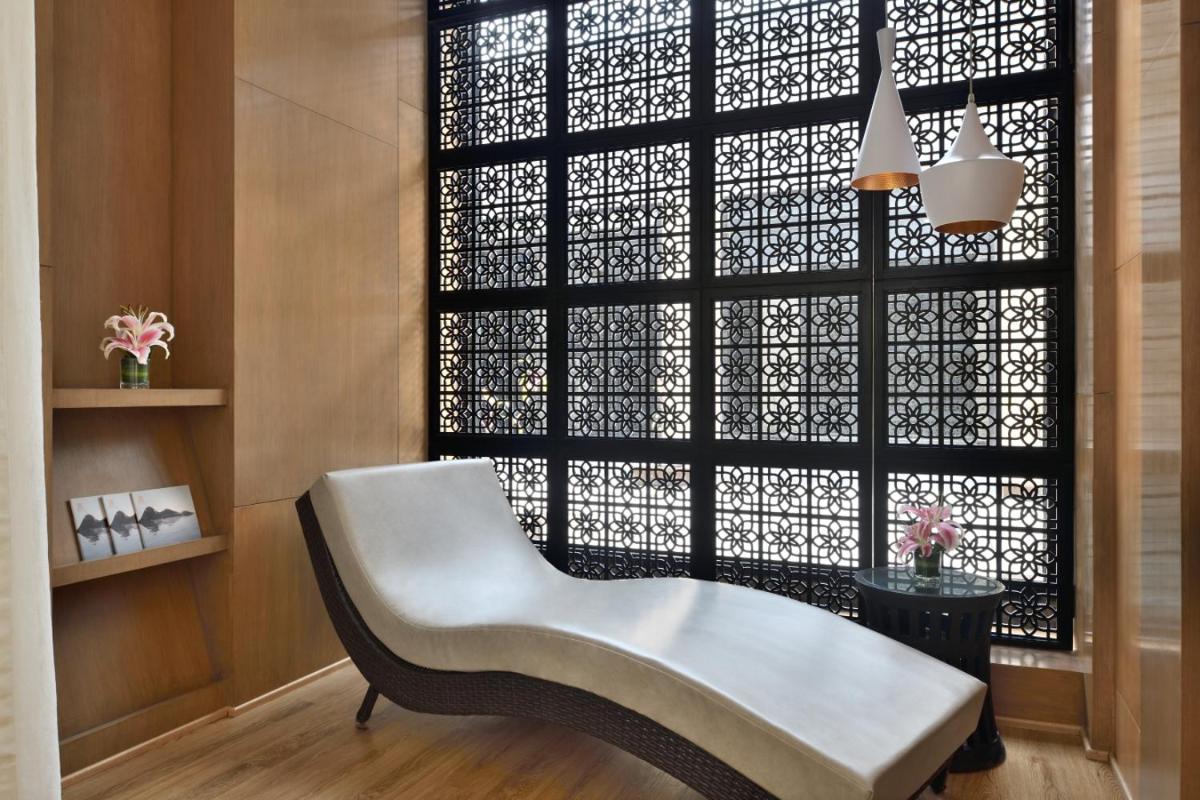 a white chair sitting in front of a window at Marriott Executive Apartment - Lakeside Chalet, Mumbai in Mumbai