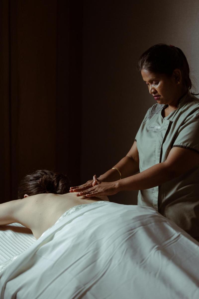 a woman is giving a man a massage at Marriott Executive Apartment - Lakeside Chalet, Mumbai in Mumbai
