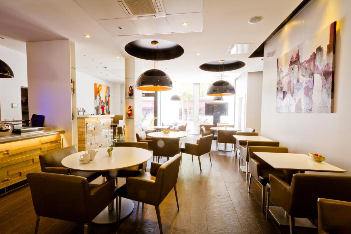 un restaurant avec des tables et des chaises dans une salle dans l'établissement Hôtel et Spa La Villa K - Basel Airport, à Saint-Louis