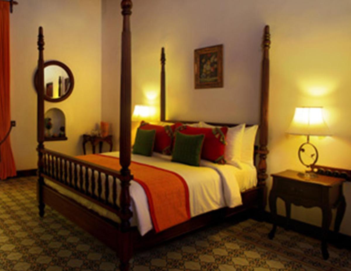 a bedroom with a large bed and a mirror at Forte Kochi in Cochin