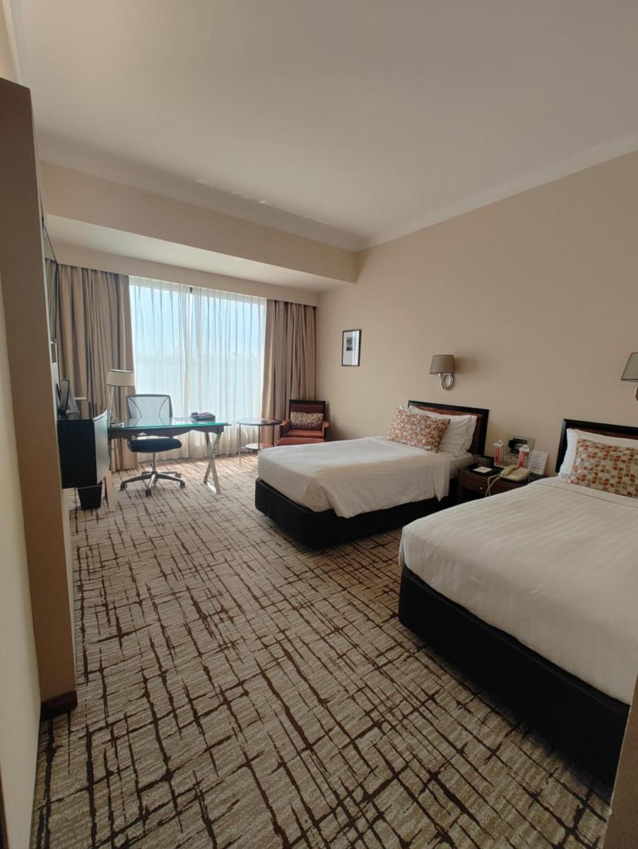 a hotel room with two beds and a desk at Hotel Marine Plaza in Mumbai