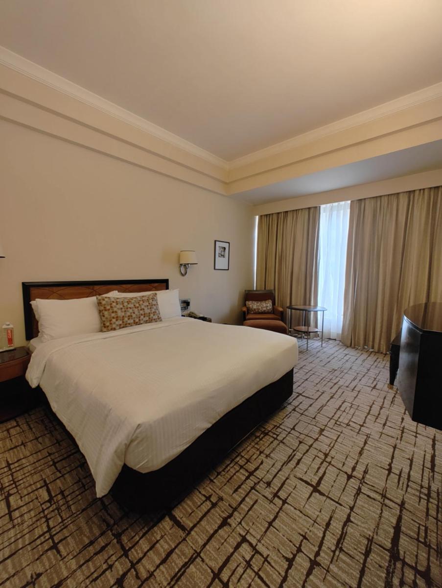 a hotel room with a large bed and a chair at Hotel Marine Plaza in Mumbai
