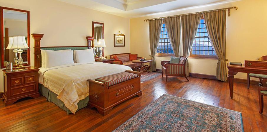 a bedroom with a bed and a desk and a chair at The Oberoi Cecil in Shimla