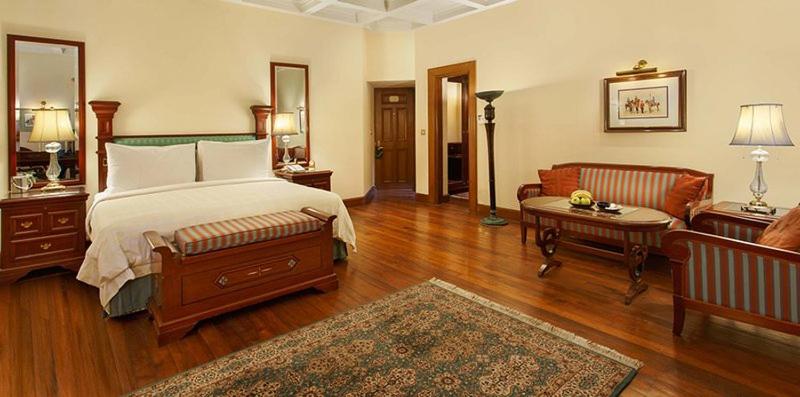 a bedroom with a bed and a living room at The Oberoi Cecil in Shimla