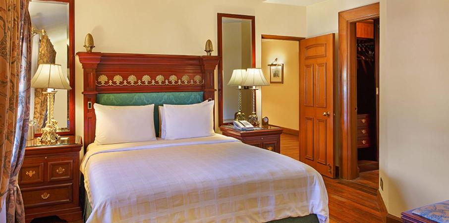 a bedroom with a large bed and a mirror at The Oberoi Cecil in Shimla