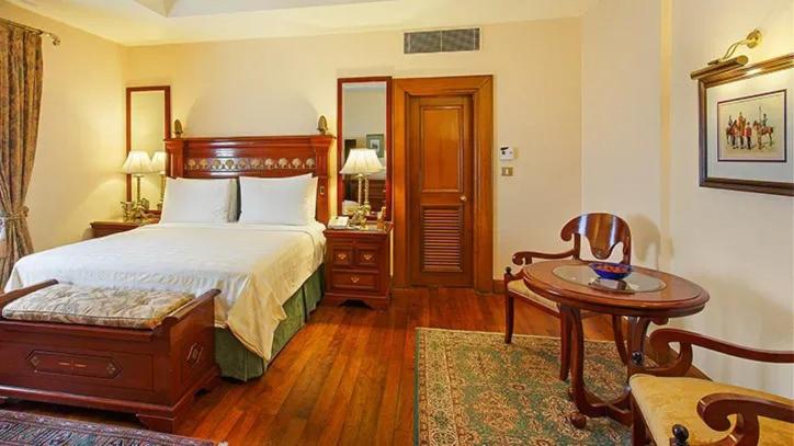a bedroom with a bed and a table and a desk at The Oberoi Cecil in Shimla