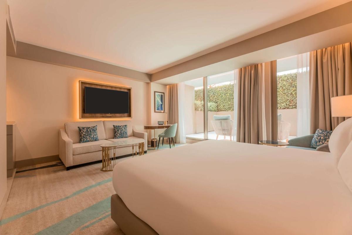 um quarto de hotel com uma cama e uma sala de estar em Legacy Hotel Cascais, Curio Collection By Hilton em Cascais