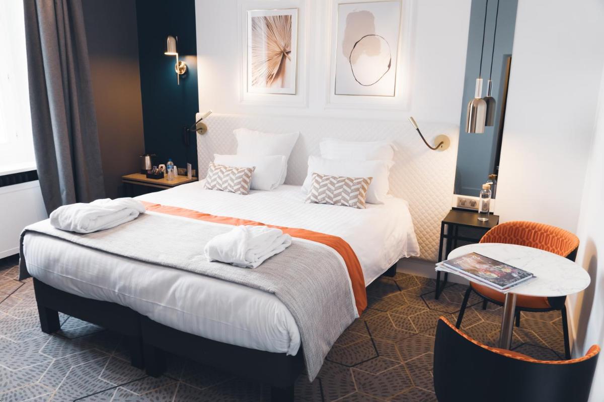 une chambre d'hôtel avec deux lits et une table dans l'établissement Oceania Hôtel d'Anjou Angers, à Angers