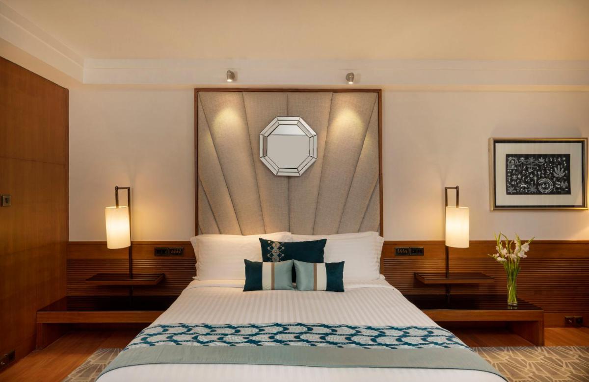 a bedroom with a large bed with blue and white pillows at InterContinental Marine Drive Mumbai by IHG in Mumbai