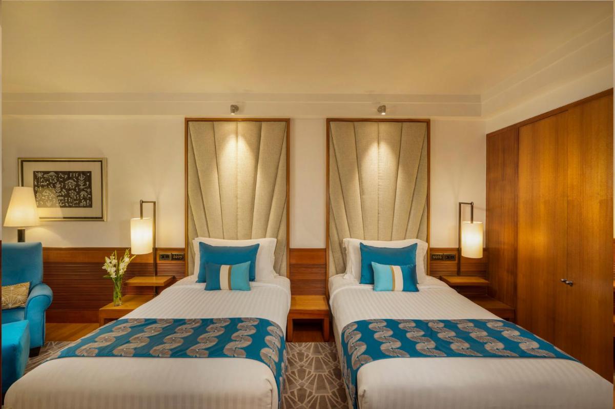 two beds in a hotel room with blue pillows at InterContinental Marine Drive Mumbai by IHG in Mumbai