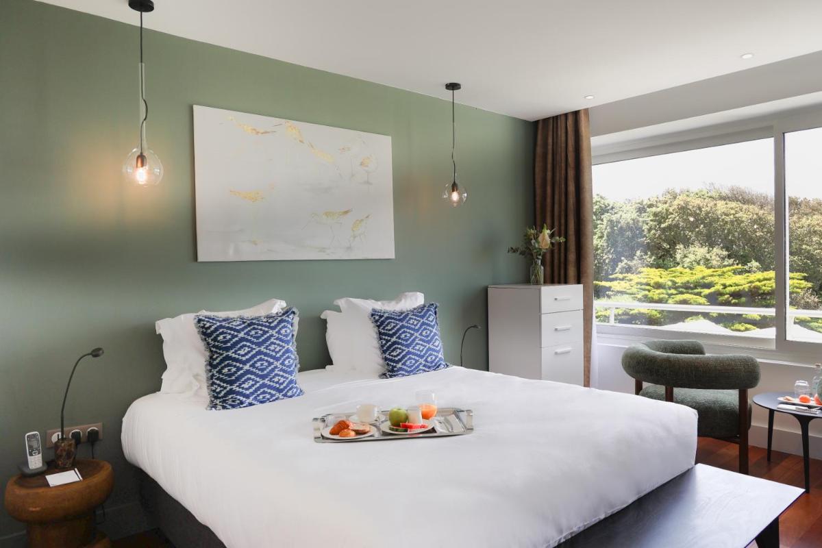 - une chambre d'hôtel avec un lit et un plateau de nourriture dans l'établissement Hôtel & Spa Le Grand Large, à Dolus-d'Oléron
