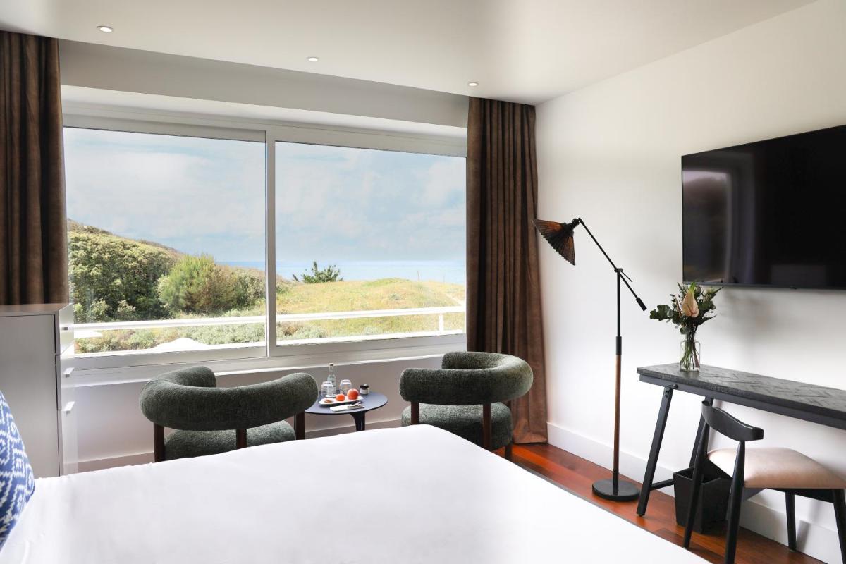 une chambre d'hôtel avec un lit et une grande fenêtre dans l'établissement Hôtel & Spa Le Grand Large, à Dolus-d'Oléron 37 autres photos