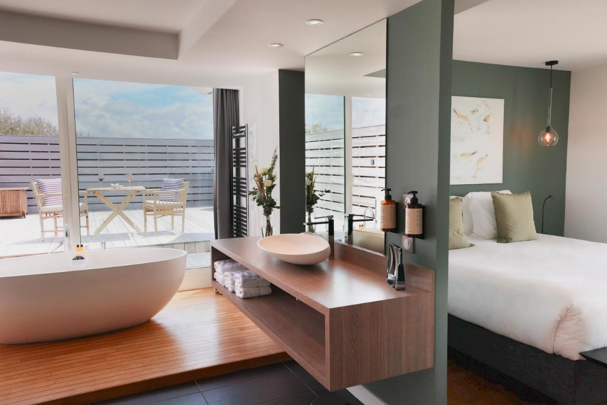 - une chambre avec une baignoire, un lit et un balcon dans l'établissement Hôtel & Spa Le Grand Large, à Dolus-d'Oléron