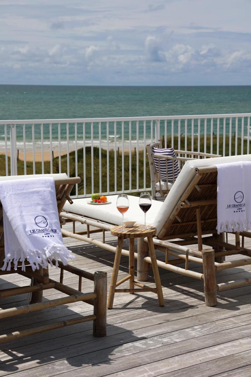 une table et des chaises sur une terrasse près de la plage dans l'établissement Hôtel & Spa Le Grand Large, à Dolus-d'Oléron