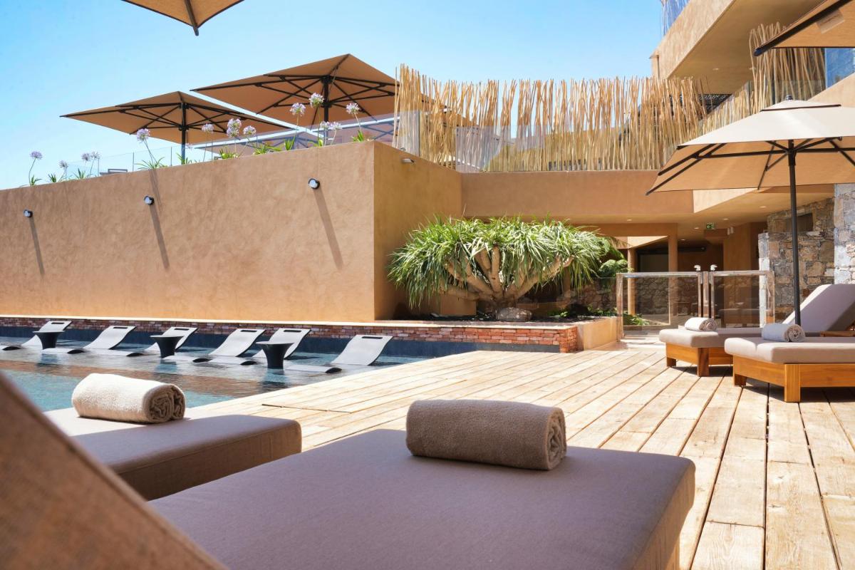 une piscine avec chaises longues et parasols dans l'établissement Les Regalia Hôtel & Spa, à Sainte-Lucie de Porto-Vecchio
