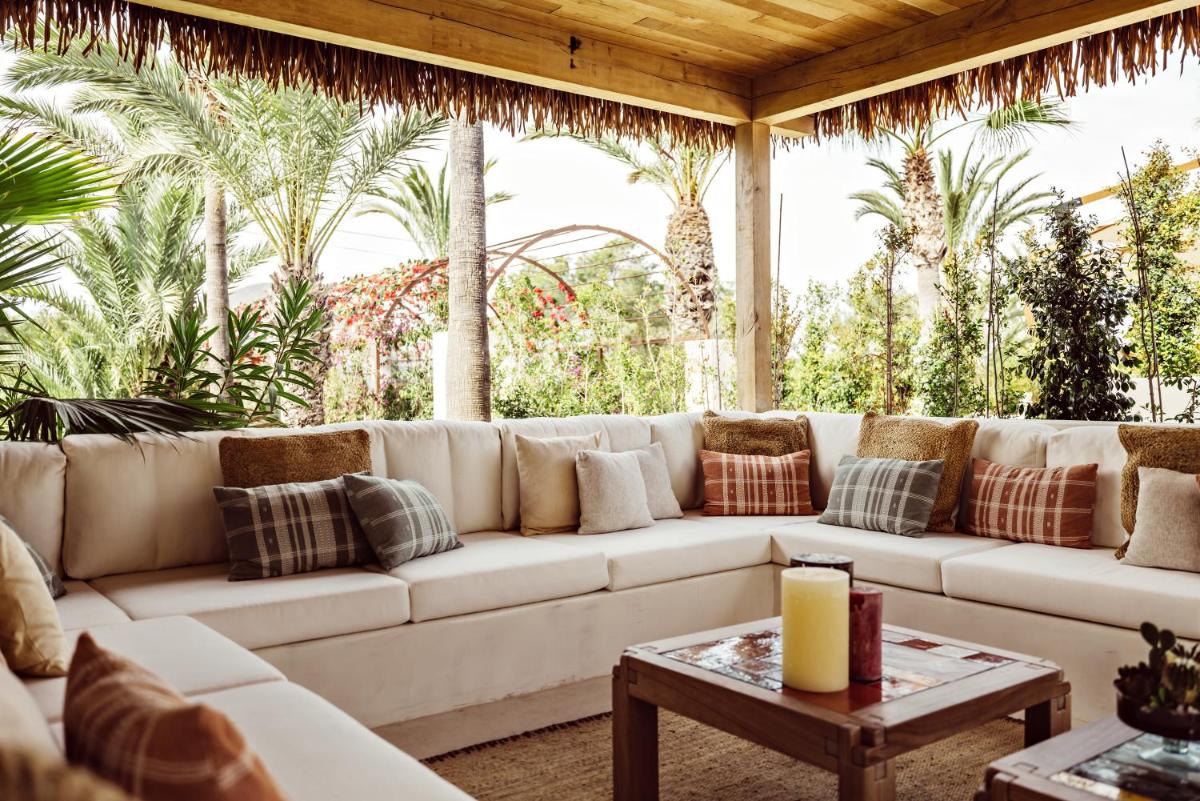 Un gran sofá blanco en una sala de estar con palmeras. en Petunia Ibiza, a Beaumier hotel, en Cala Vadella