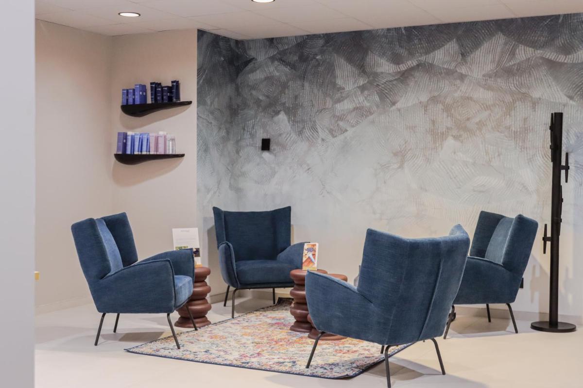 une salle d'attente avec des chaises bleues et une table dans l'établissement Hôtel Best of Both - Divonne-les-Bains, à Divonne-les-Bains