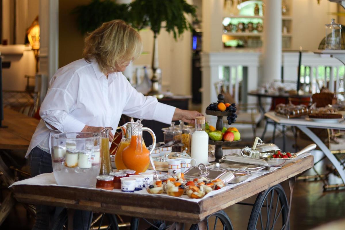 une femme debout dans une cuisine préparant de la nourriture sur un chariot dans l'établissement Brindos, Lac & Château - Relais & Châteaux - Anglet Biarritz, à Anglet